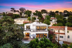 A multi-story house with a balcony, large windows, and a view of surrounding houses. - 6BR Hilltop Home + Game Lounge + Views | Los Feliz, LA | Edendale (Los Angeles)