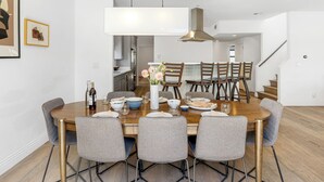 Un comedor moderno con una mesa de madera, sillas tapizadas en gris y un jarrón con flores.