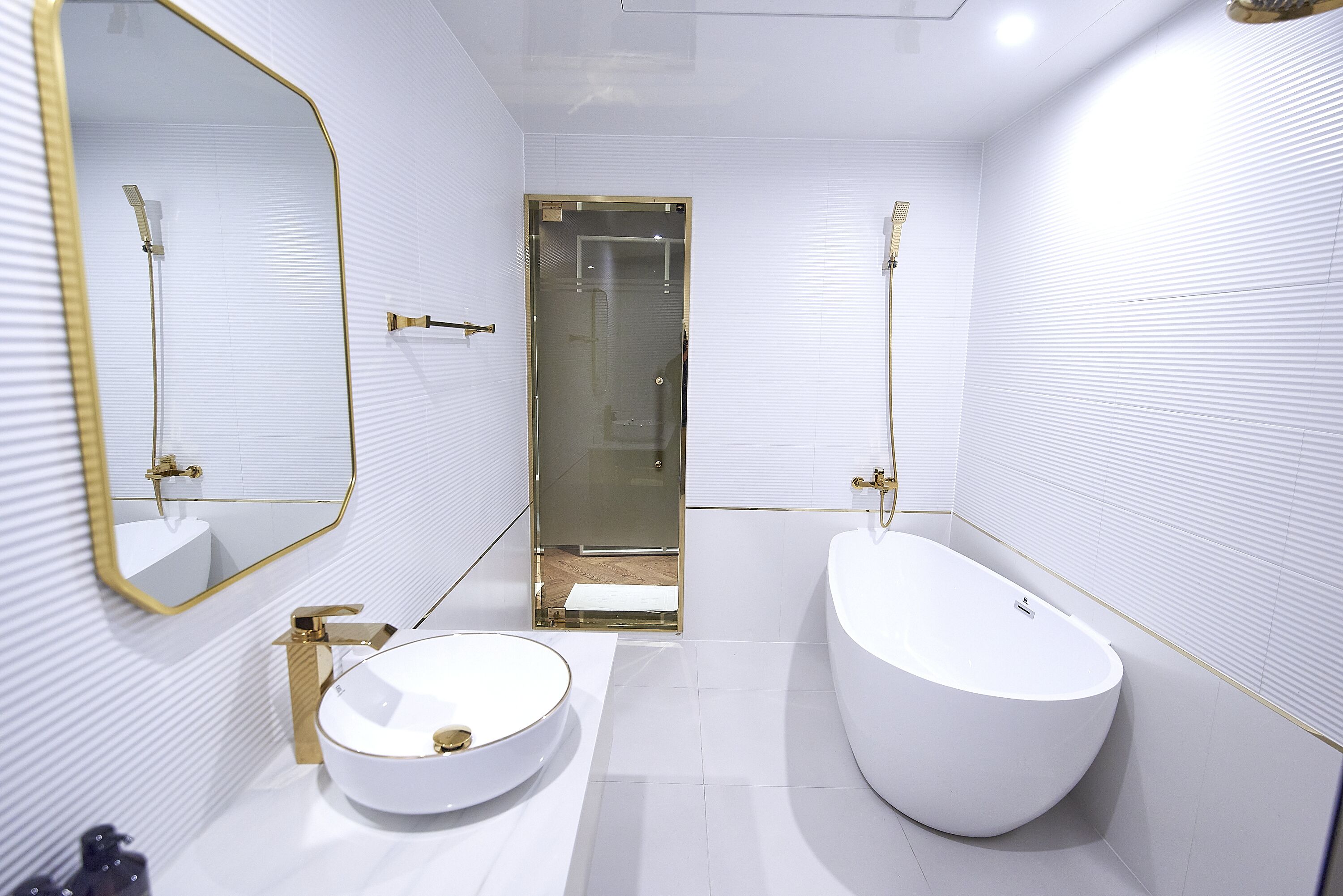 A modern bathroom with a round sink, a freestanding bathtub, and a glass-enclosed shower area.