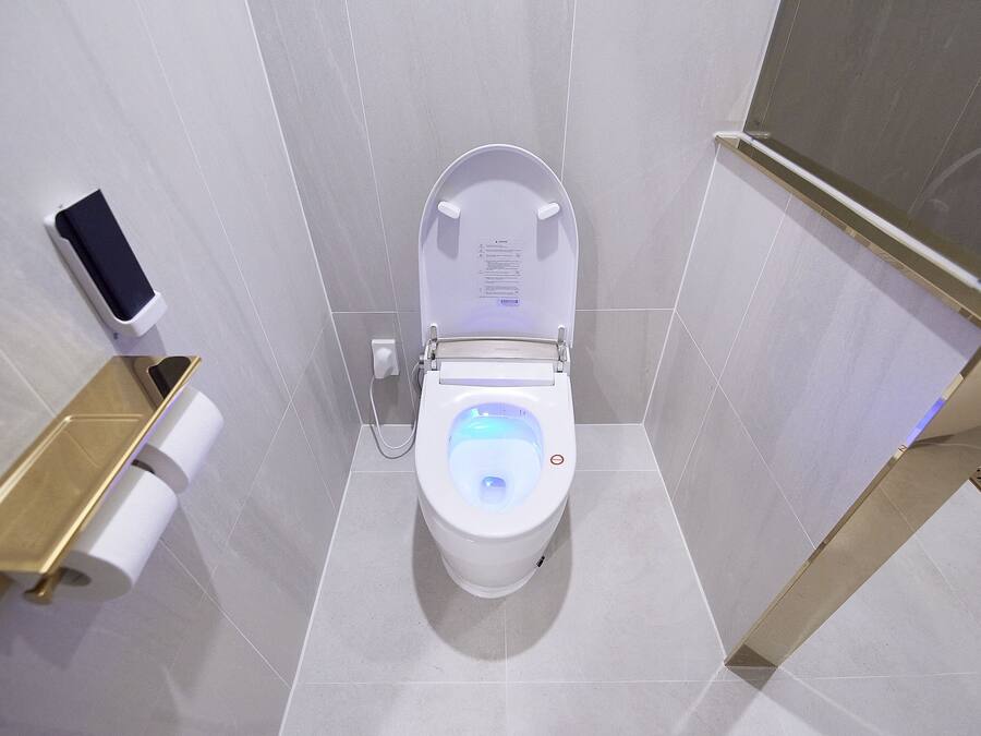 Des toilettes modernes dotées d’un écran numérique, d’un porte-rouleau de papier toilette et d’un distributeur de gel hydroalcoolique.