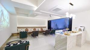 A modern conference room with a large screen, a seating area with a sofa and chairs, and a marble reception desk. - Den Basta Signature Hotel (Busan)
