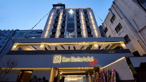 The exterior of Den Basta hotel with a prominent sign, a modern architectural design, and a clear sky. - Den Basta Signature Hotel (Busan)