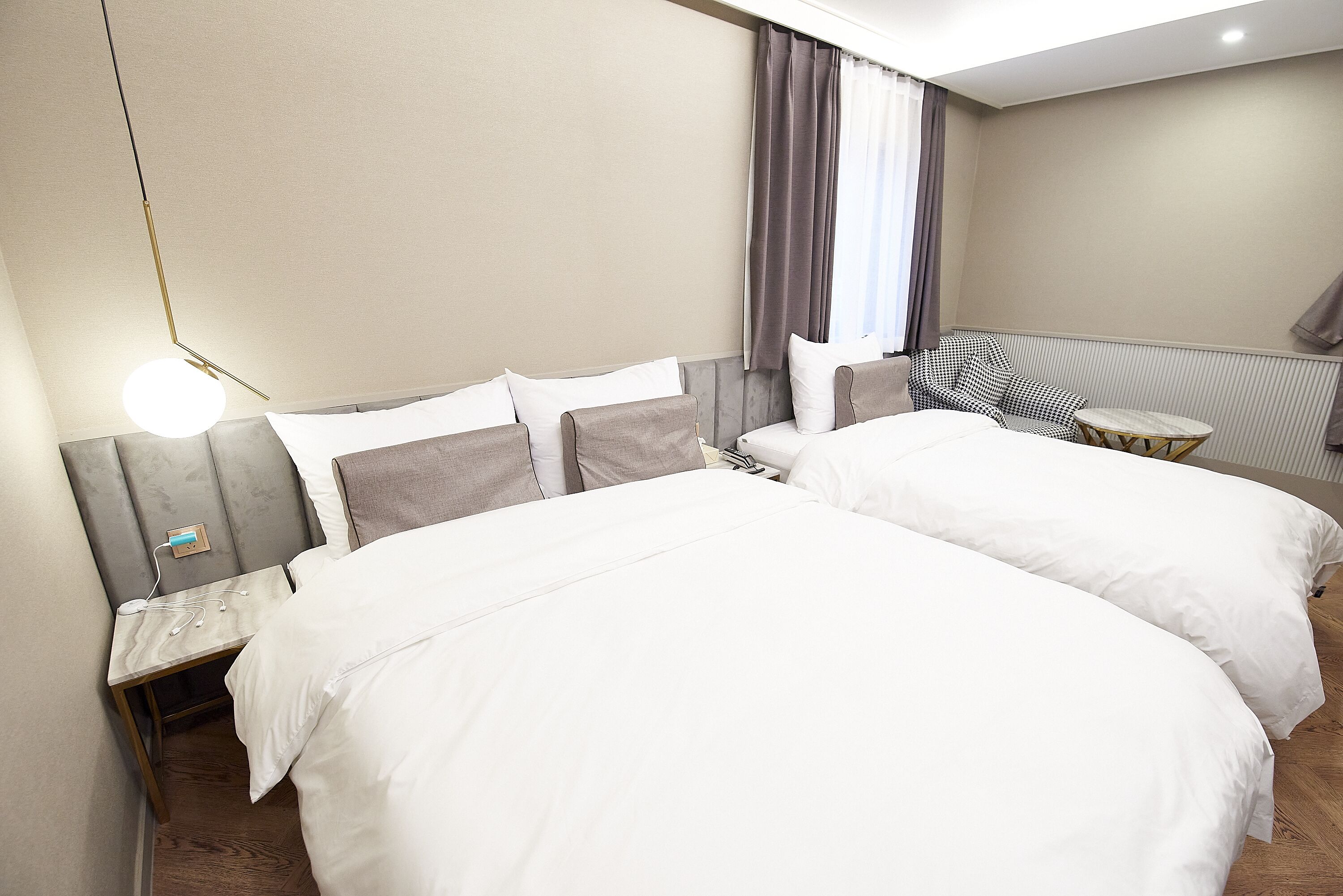 Una habitación de hotel con dos camas, una mesita, una silla y una lámpara.