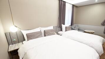 Una habitación de hotel con dos camas, una mesita, una silla y una lámpara.