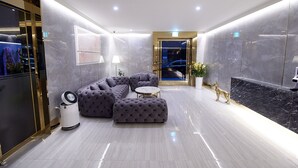 A modern lobby with a sectional sofa, a round table, and a potted plant. - Den Basta Signature Hotel (Busan)