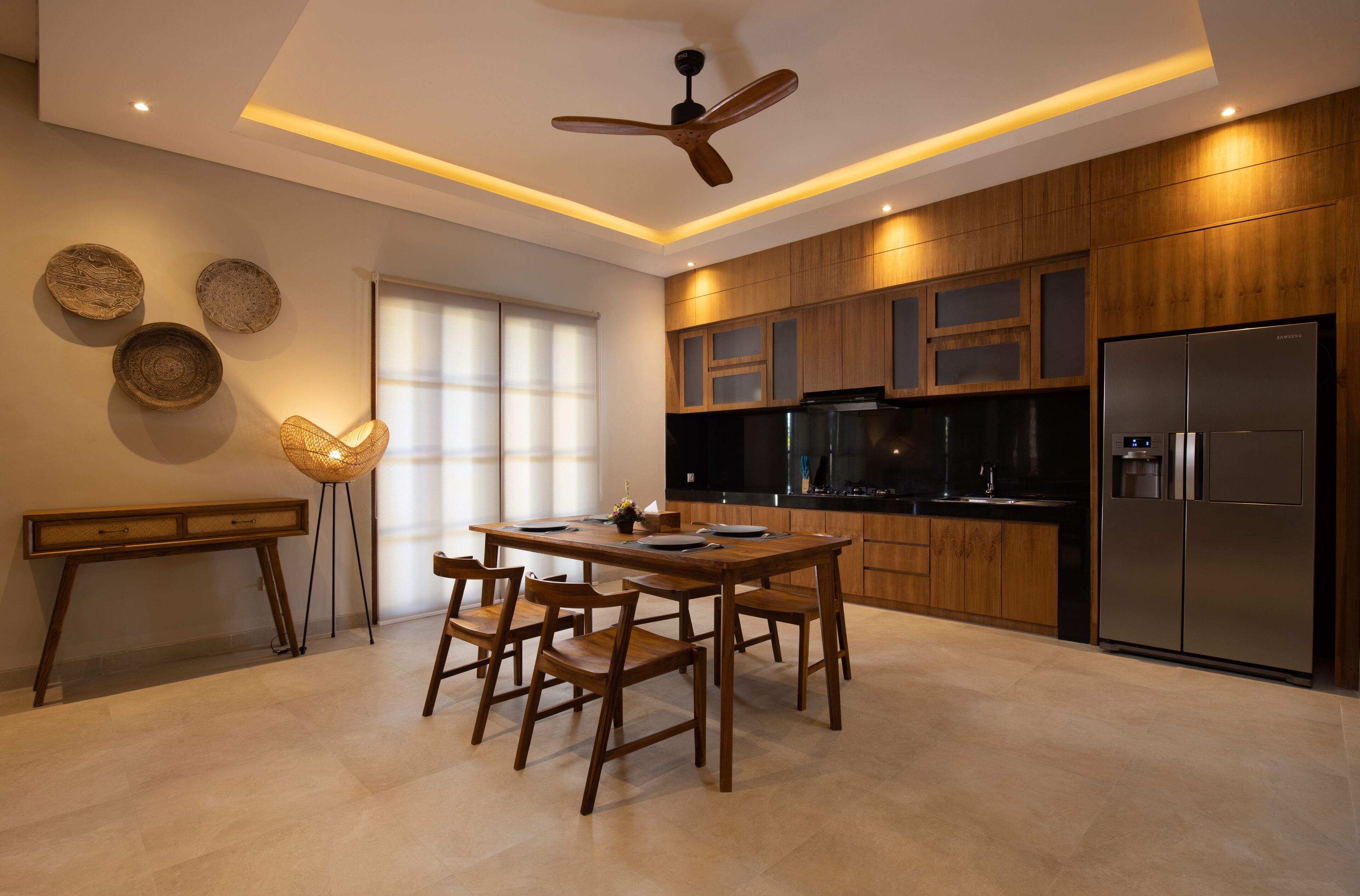A modern kitchen with wooden cabinets, a stainless steel refrigerator, and a dining area with a table and chairs.
