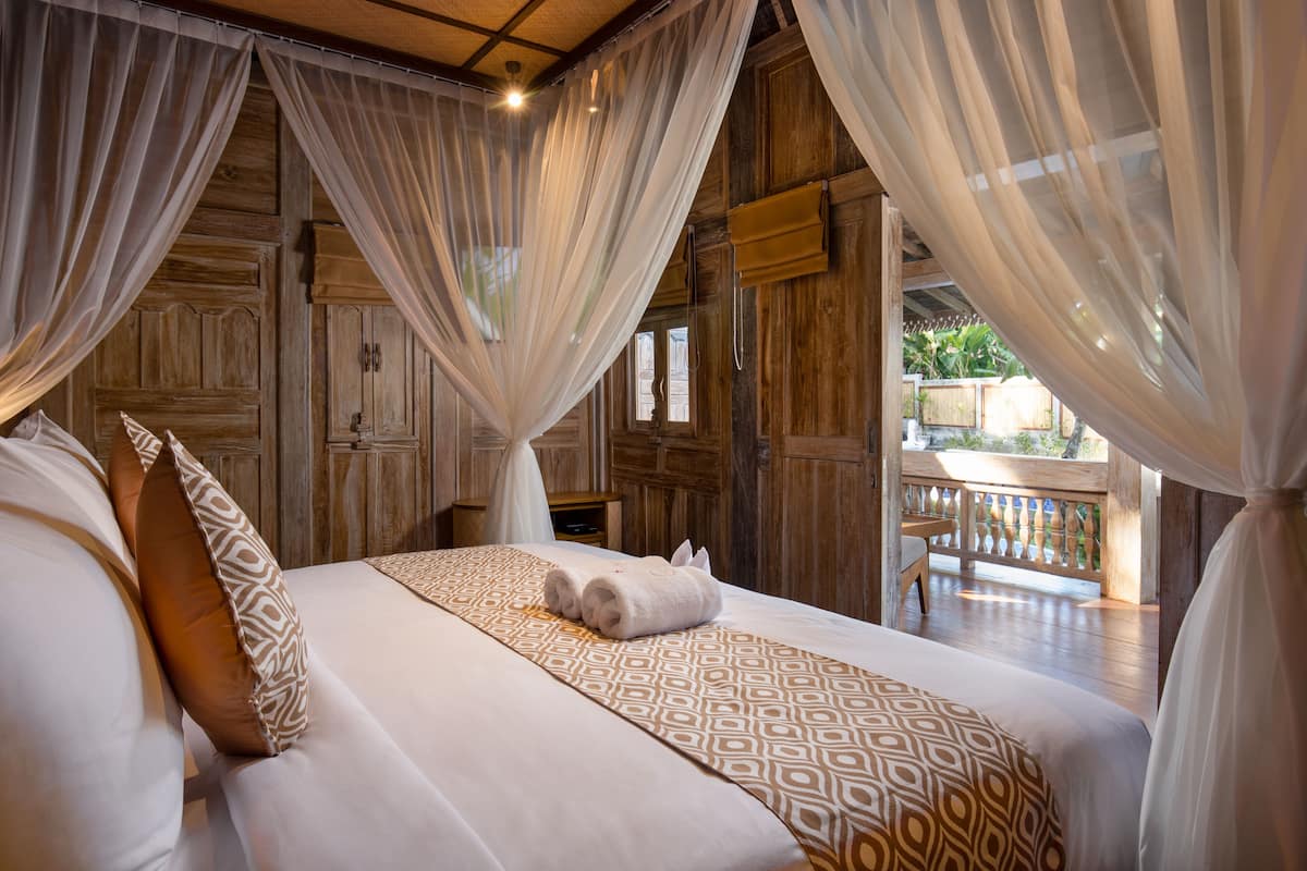 Um quarto espaçoso com uma cama grande, paredes de madeira e uma varanda com guarda-corpo de madeira.