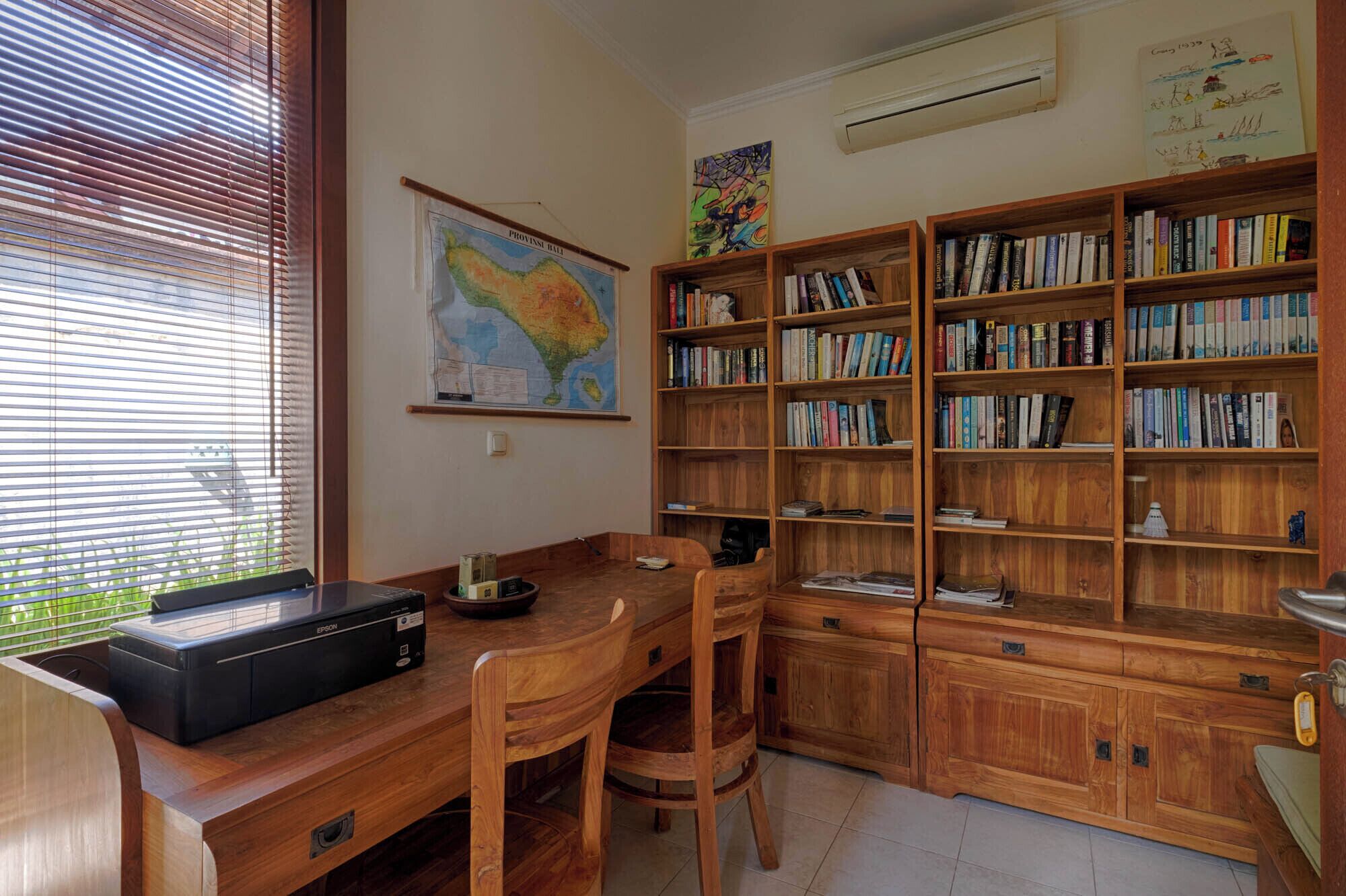 Une salle d’étude équipée d’un bureau en bois, de chaises, d’une bibliothèque et d’une carte accrochée au mur.