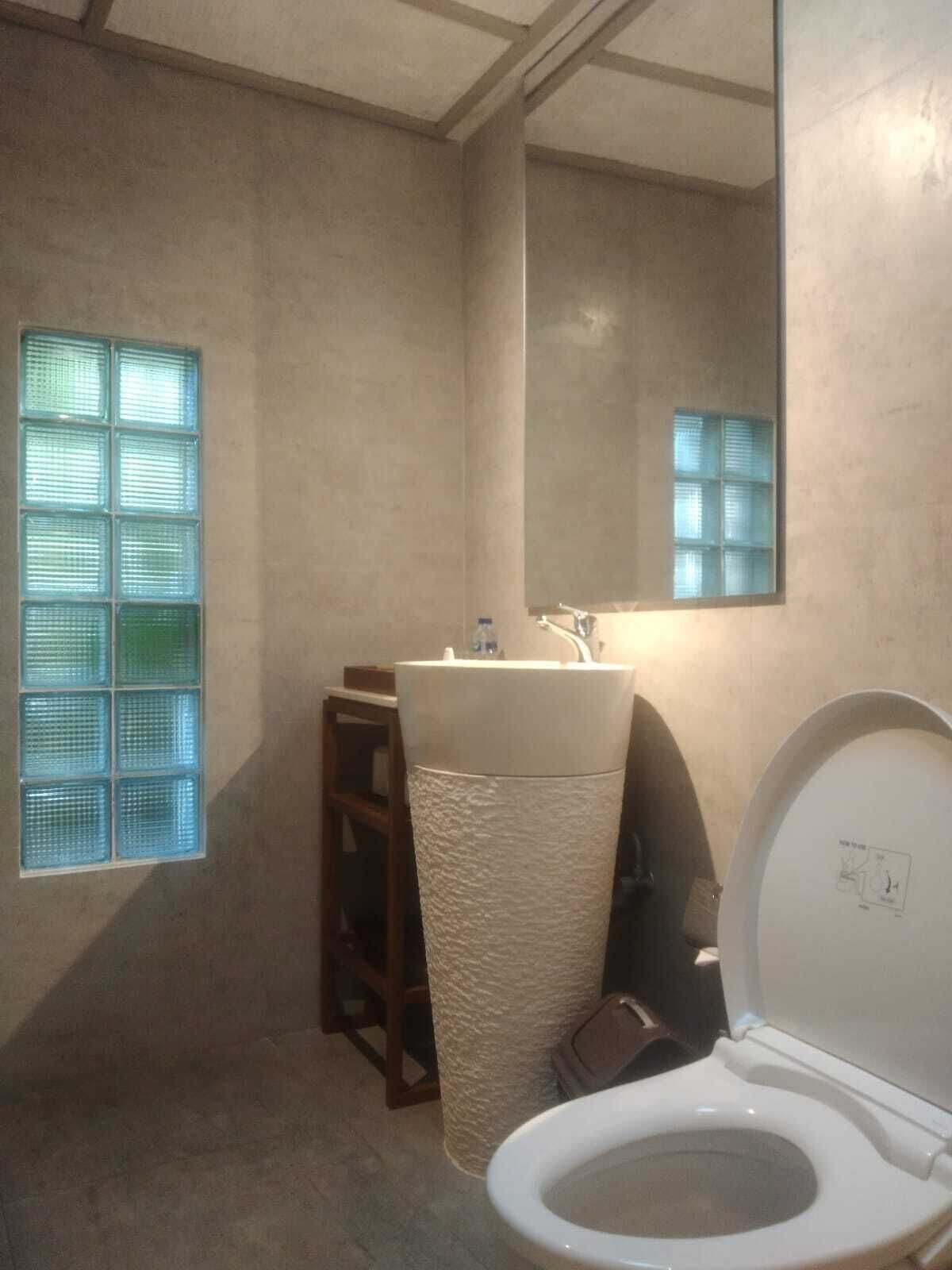 A bathroom with a toilet, sink, and mirror.