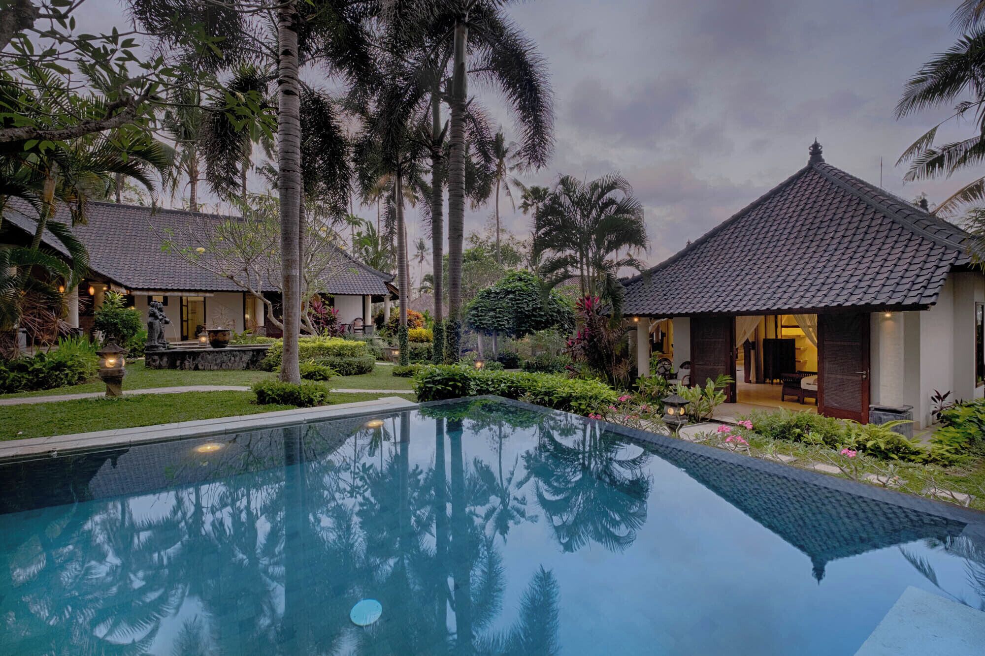 A resort with a swimming pool, palm trees, and traditional-style buildings.