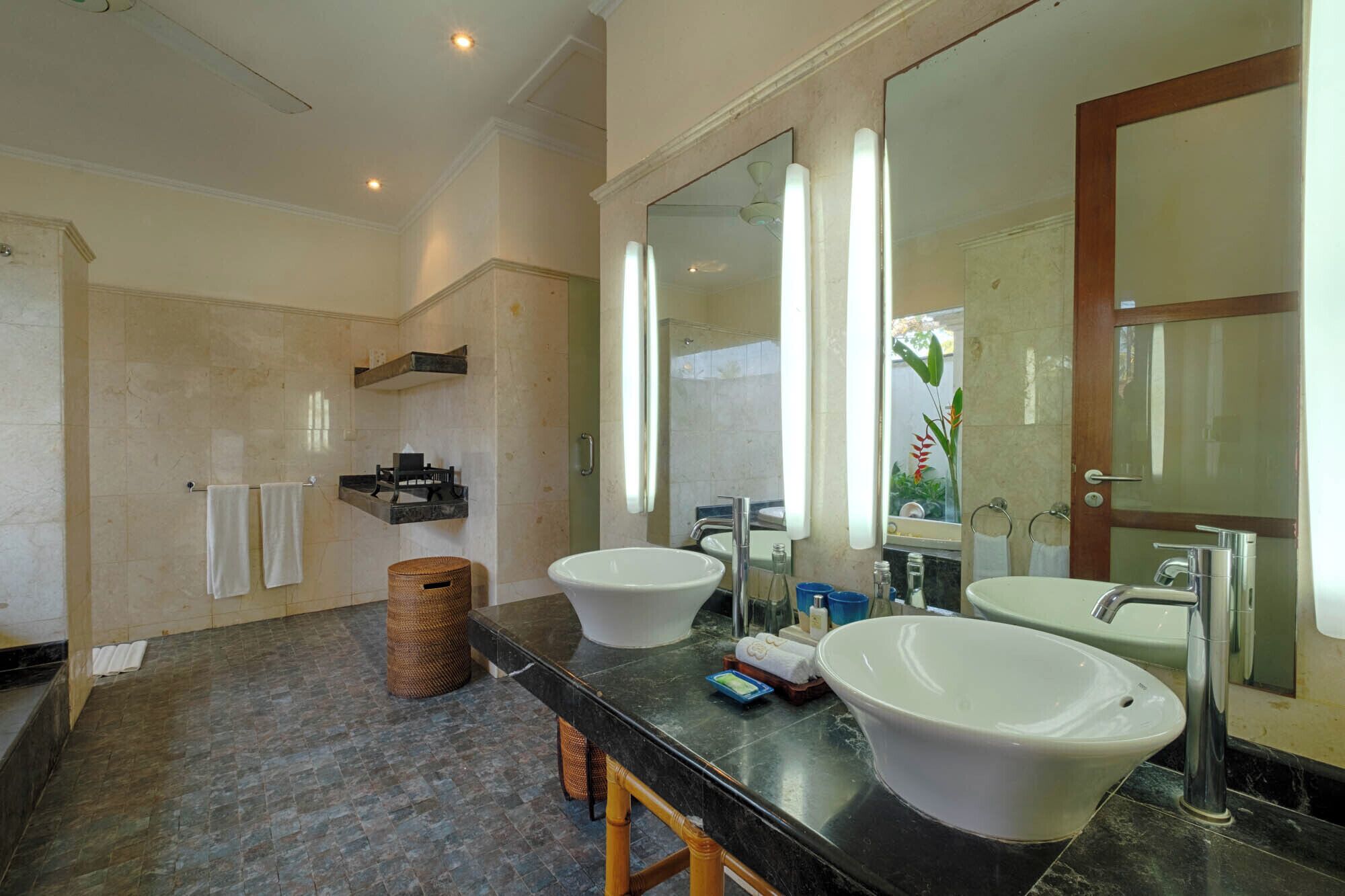 A modern bathroom with two sinks, a large mirror, and a shower area.