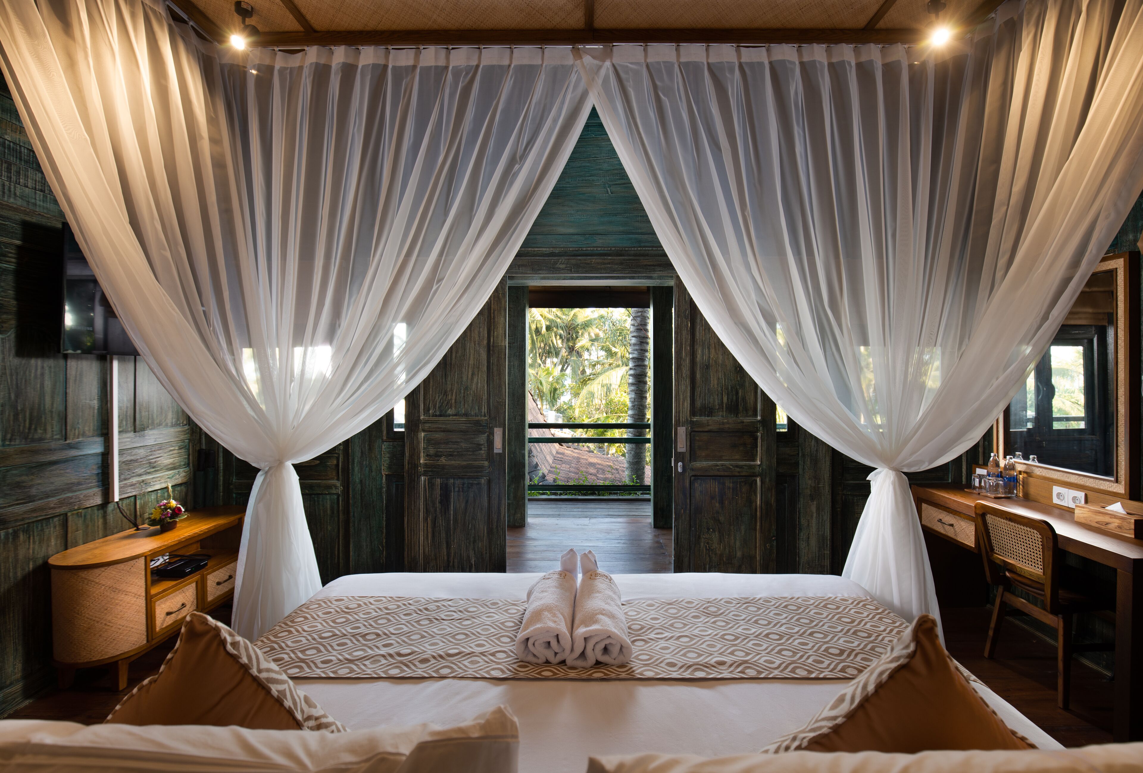 A bedroom with a bed, a desk, and a view of the outdoors.