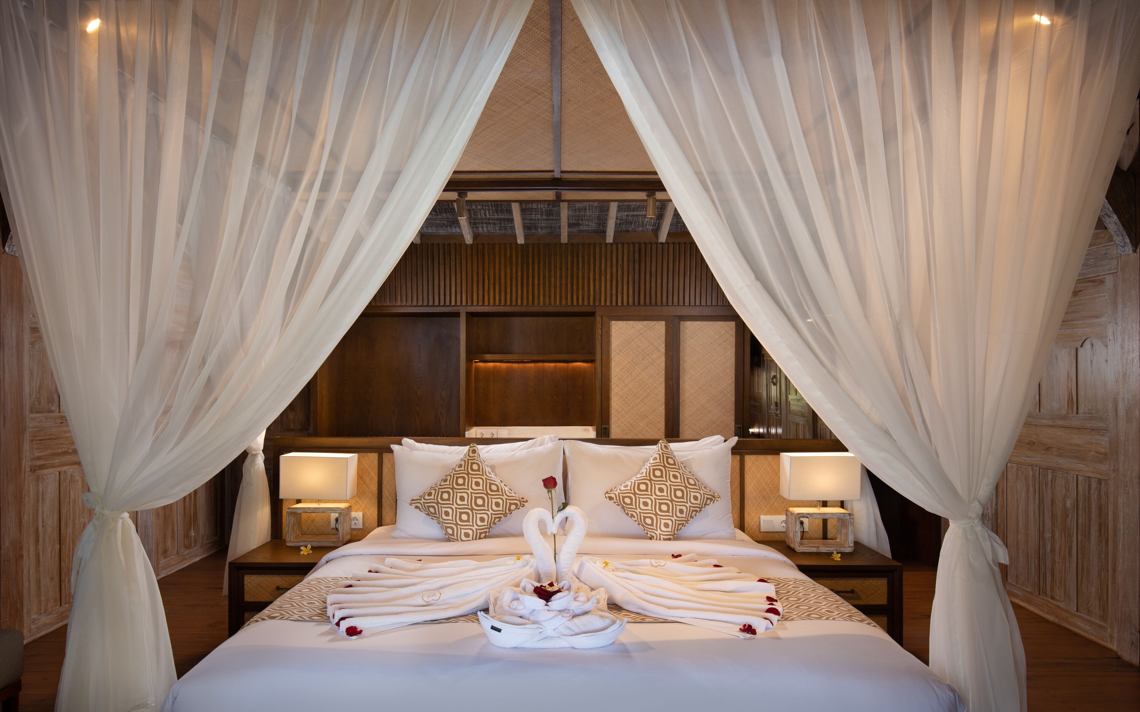 A luxurious hotel room with a large bed, white linens, and a canopy.