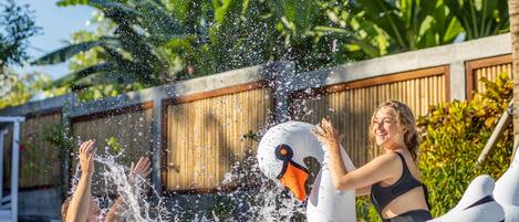 A swimming pool with inflatable swan floats and a person enjoying the water.