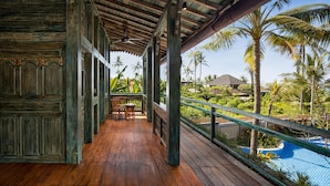 A wooden deck with a view of a swimming pool and palm trees.