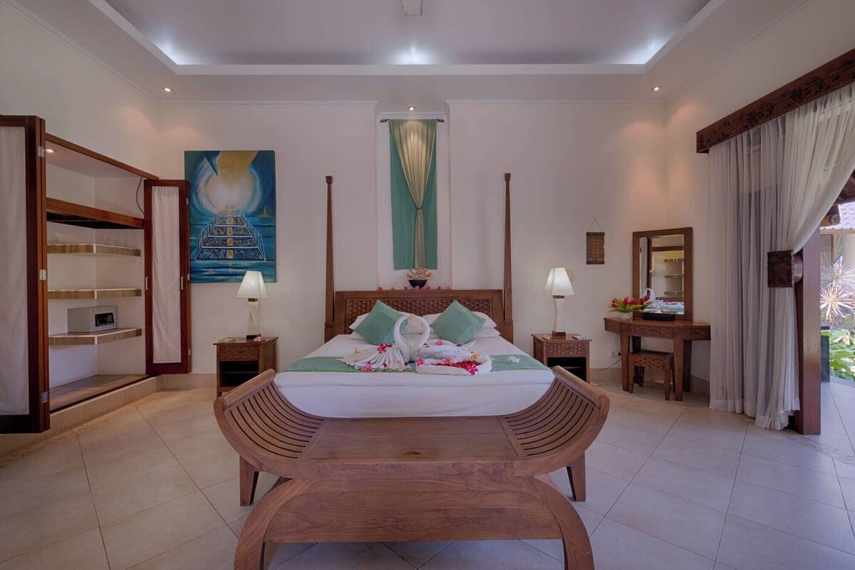 Quarto de hotel com uma cama grande, móveis de madeira, um quadro na parede e vista para o exterior.