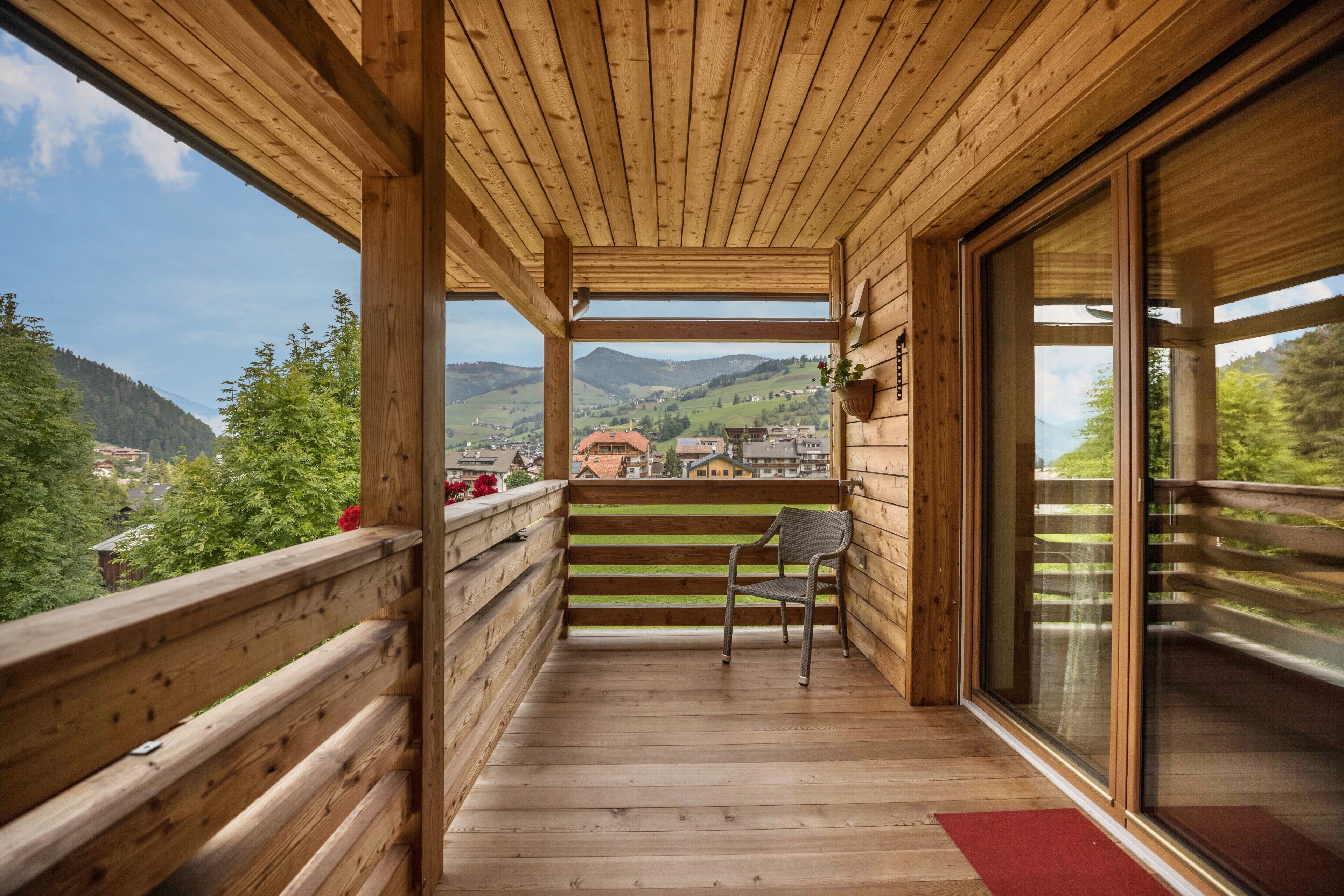 A wooden balcony with a view of a town and mountains.