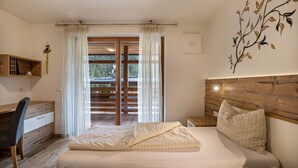 Una camera da letto con un letto, una scrivania, una sedia, una testiera in legno e vista attraverso una porta vetrata.