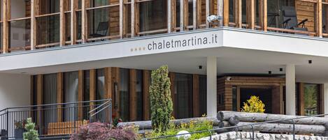 Un bâtiment moderne avec une façade en bois, un balcon agrémenté de chaises et une enseigne indiquant « chalematrina.it ».