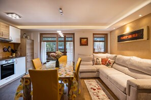 A modern kitchen with a dining table, yellow chairs, and a sofa in a living area.