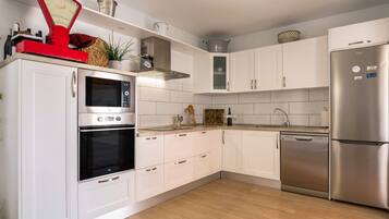 Una cocina moderna con armarios blancos, electrodomésticos de acero inoxidable y piso de madera.