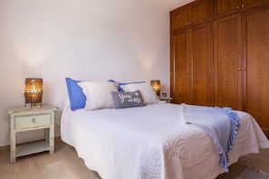 A bedroom with a bed, nightstands, a wardrobe, and decorative lamps.