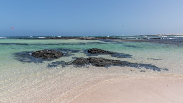 A beach with clear water, rocks, and a distant view of the ocean. - Holiday Home Casa Nati with Mountain View, Wi-Fi, Shared Garden (Lajares)