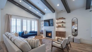 A spacious living room with a fireplace, a large sofa, a coffee table, and a dining area.
