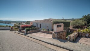 Un bâtiment d’un seul étage, doté d’un toit en tuiles, de murs en pierre et d’un petit jardin agrémenté de fleurs rouges.