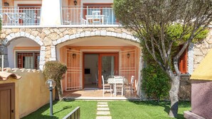 Un bâtiment à deux étages doté d’une entrée en arc de pierre, d’un balcon avec des balustrades blanches et d’un petit patio aménagé avec une table et des chaises.
