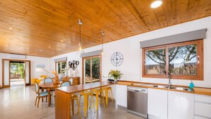 A modern kitchen with wooden cabinets, a stainless steel sink, and a large island with bar stools. - Vacation Home Santa Eulàlia 54 with Wi-Fi, A/C, Pool, Garden & Terrace; Parking Available (Can Picafort)