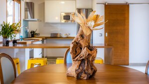 A dining table with a centerpiece of a tree trunk and corn, a yellow chair, and a wooden ceiling. - Vacation Home Santa Eulàlia 54 with Wi-Fi, A/C, Pool, Garden & Terrace; Parking Available (Can Picafort)