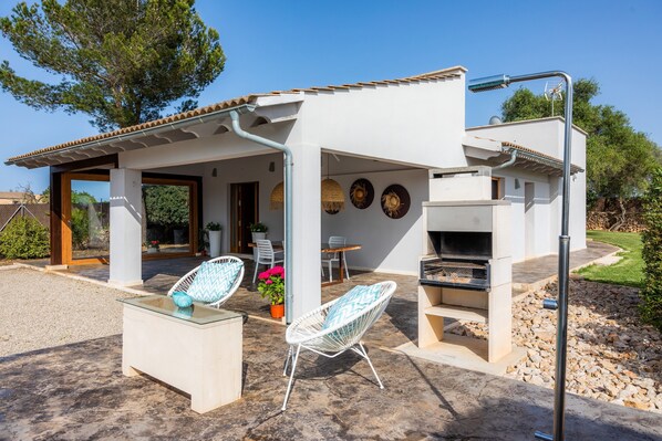 Un espace extérieur aménagé avec un barbecue, des sièges et une pergola.