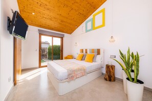 Une chambre à coucher avec un lit, un téléviseur, une plante en pot et un plafond en bois.