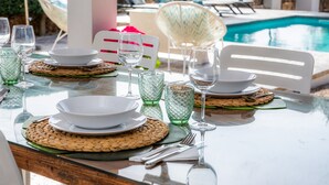A dining table set with plates, glasses, and cutlery, with a pool and lounge chairs in the background. - Vacation Home Santa Eulàlia 54 with Wi-Fi, A/C, Pool, Garden & Terrace; Parking Available (Can Picafort)