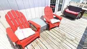 A wooden deck with two red Adirondack chairs and a small table. - Bonita-Jamaica Beach w/Pool,Dog Friendly,kayak/pdlebrd,big yard,8min walk 2beach (Jamaica Beach)