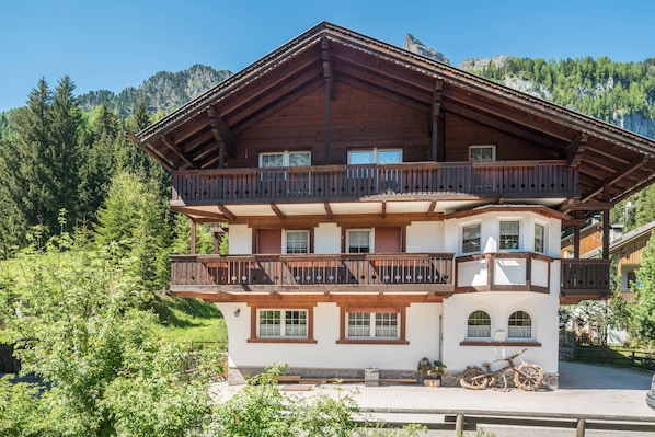 Ein mehrstöckiges Holzchalet mit Balkonen vor einer Bergkulisse.