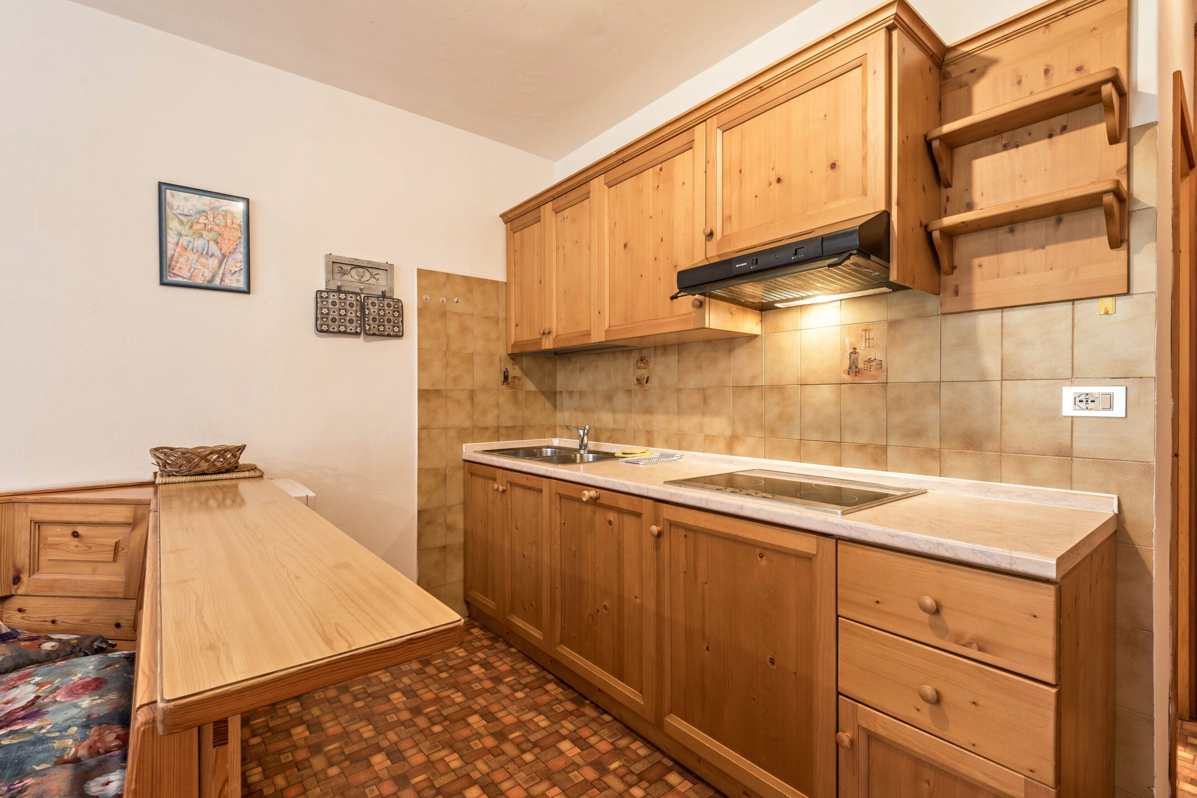 A compact kitchen with wooden cabinets, a built-in sink, and a tiled backsplash.