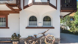 Un edificio rústico con balcón de madera, una bicicleta y una planta en maceta.