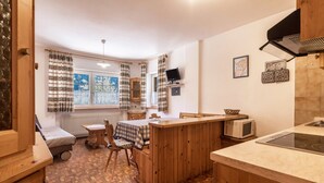 Una cocina compacta con una isla de madera, un comedor con mesa y sillas, un microondas y un televisor montado en la pared.