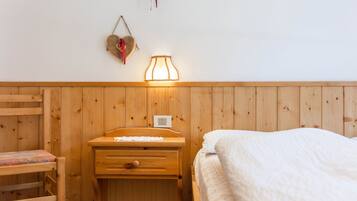 Ein Zimmer mit Holzwänden, einem Bett, einem Schreibtisch und einem Stuhl.