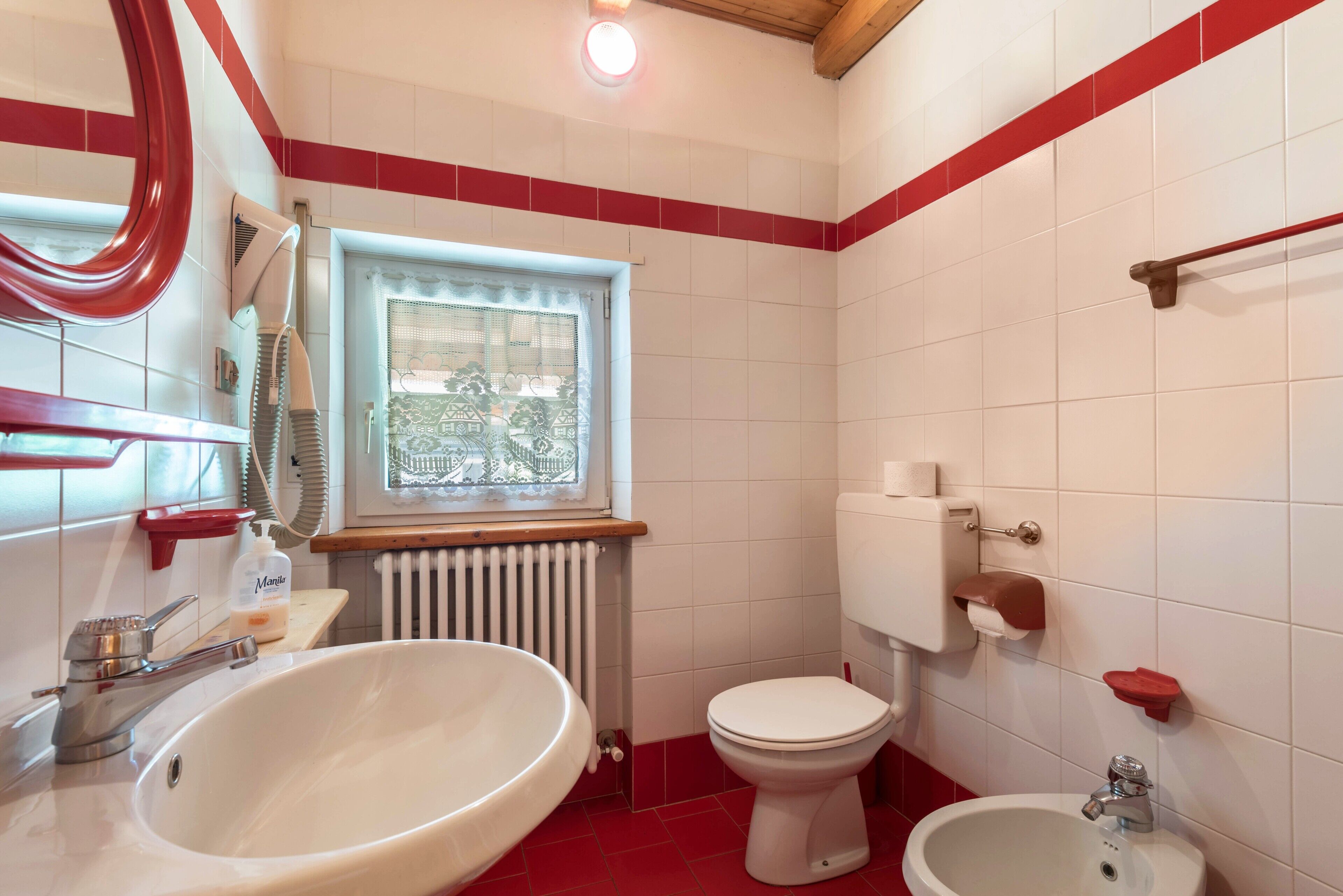 Un baño con lavamanos, bidé, inodoro y ventana con vistas.