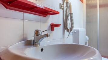 A bathroom with a white sink, red towel rack, and a hairdryer on the wall.