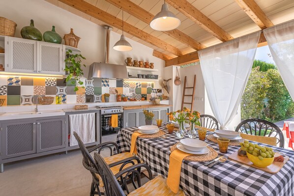 A kitchen with checkered tablecloths, a dining table set with plates and bowls, and a view of greenery outside. - Vacation Home Casa Gema with Mountain View, Pool, Wi-Fi, Garden & Terrace; Parking on Street Available (Selva)
