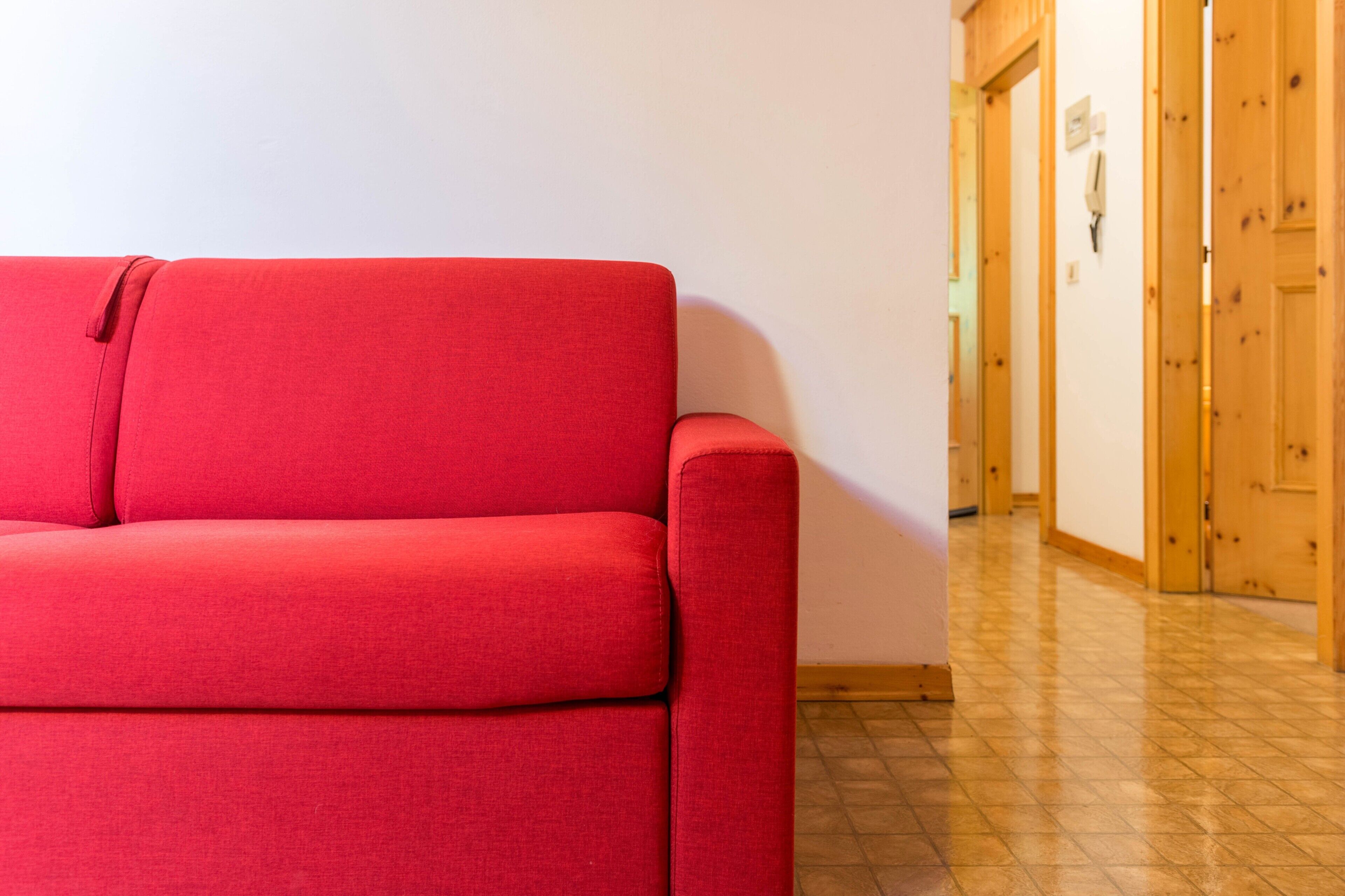 Ein rotes Sofa in einer Diele mit Holztüren und Fliesenboden.