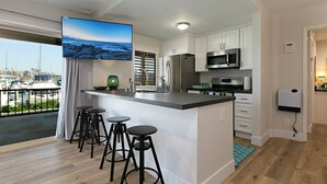 Een moderne keuken met een groot eiland, barkrukken, roestvrijstalen apparatuur en uitzicht op de jachthaven.