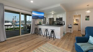 Een moderne keuken met een bar, een grote televisie en uitzicht op de jachthaven.