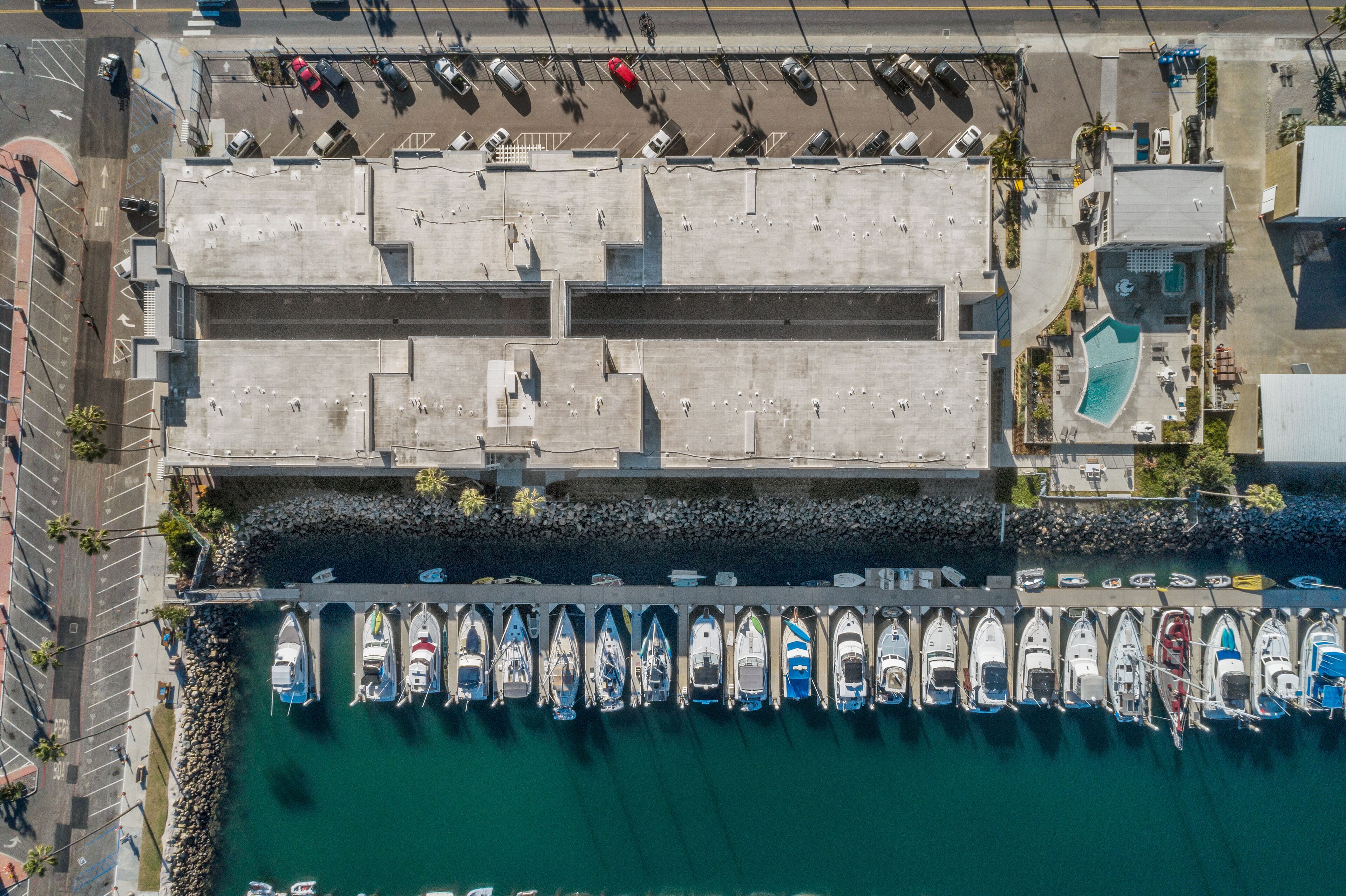 An aerial view of a marina with boats docked and a parking area above.