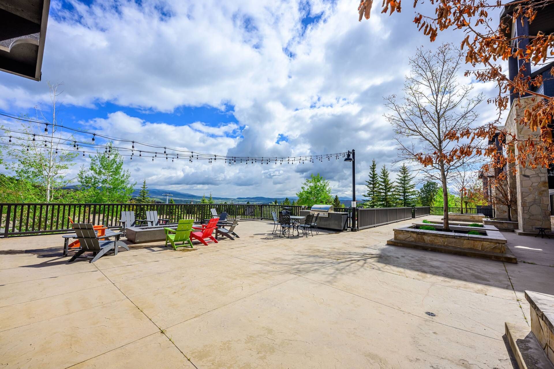 An outdoor patio with seating, a barbecue grill, and string lights.