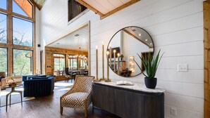 A modern interior with a large mirror, wooden flooring, and a seating area with a patterned armchair.
